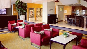 A lobby with red seating, a large plant, and a bar area. - Steigenberger Graf Zeppelin (Stuttgart)