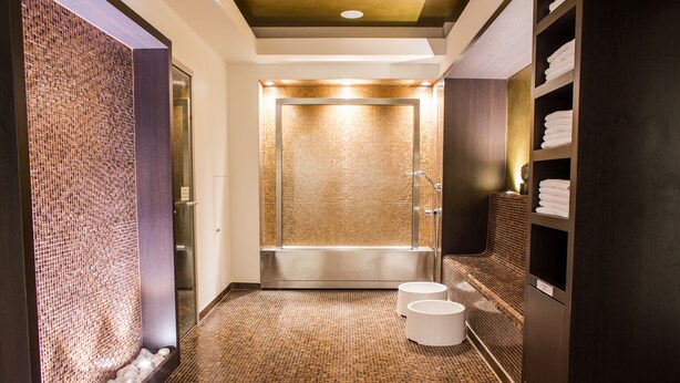 A modern bathroom with a mosaic wall, a bathtub, and a shelf with towels. - Steigenberger Graf Zeppelin (Stuttgart)