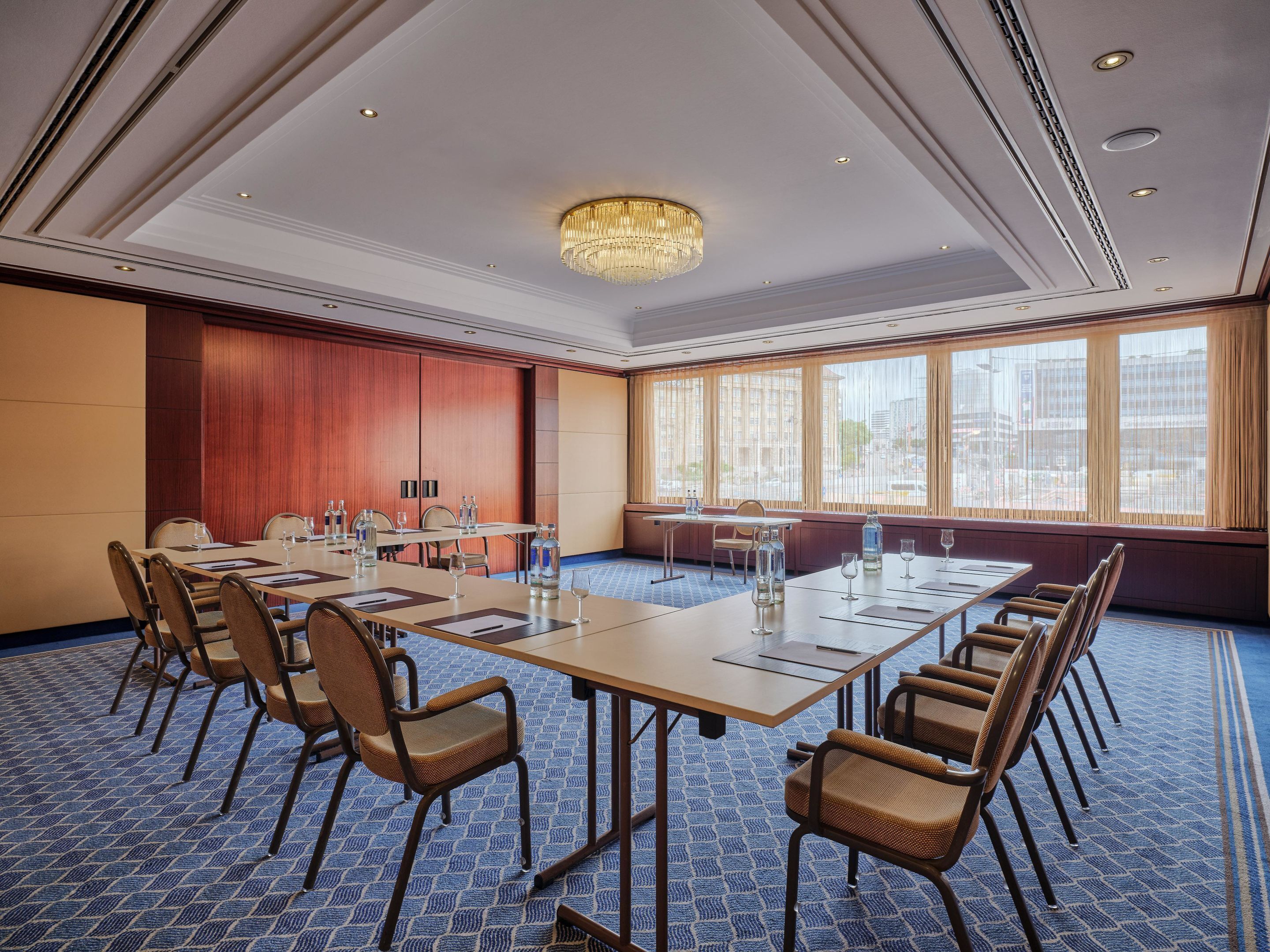 Uma sala de conferências com uma mesa grande, cadeiras e um candelabro.