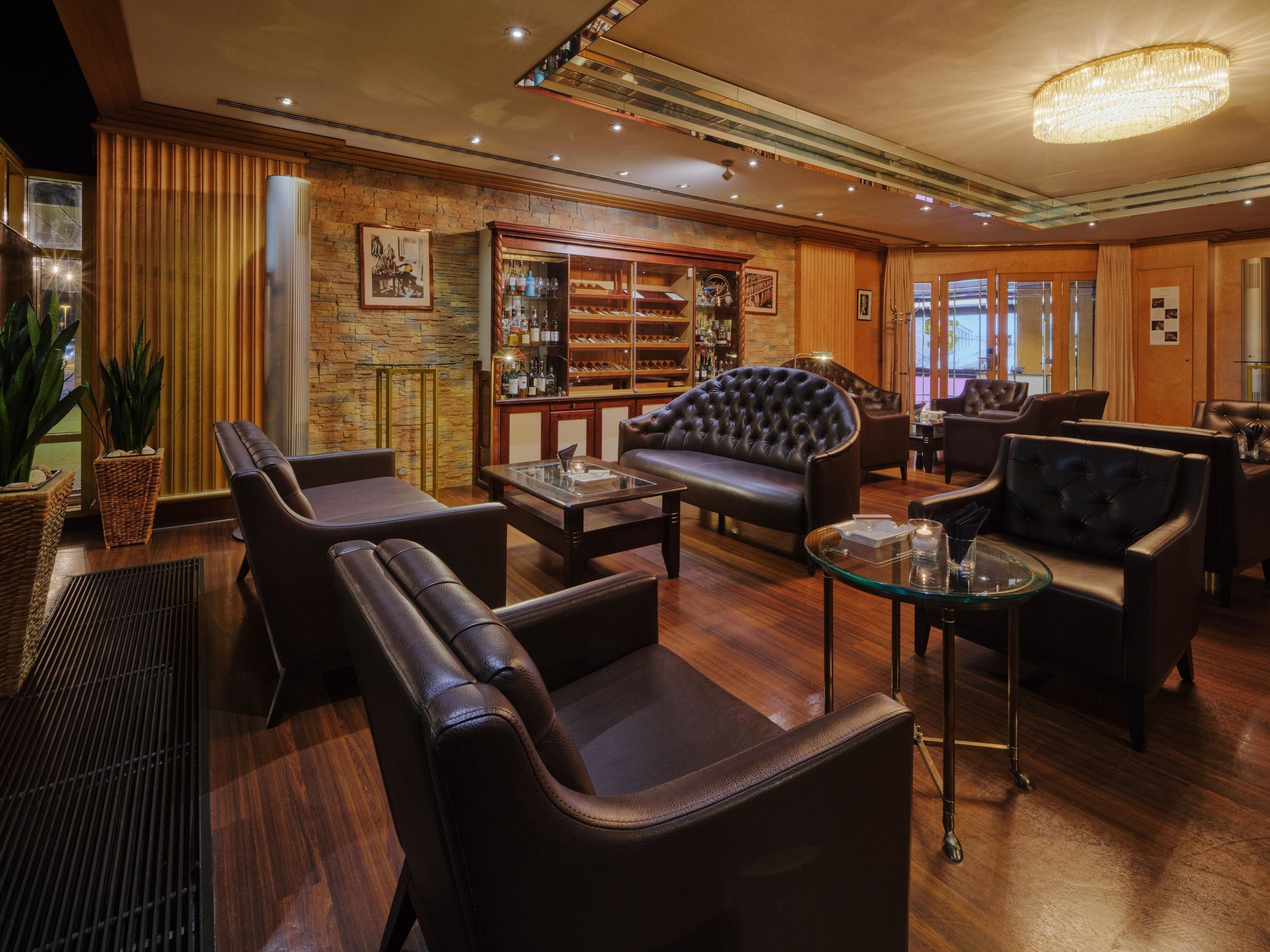 Un salón moderno con sofás de cuero, una zona de bar y una pared decorativa de piedra.