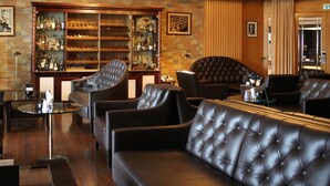A bar area with leather sofas, a glass table, and a liquor display. - Steigenberger Graf Zeppelin (Stuttgart)