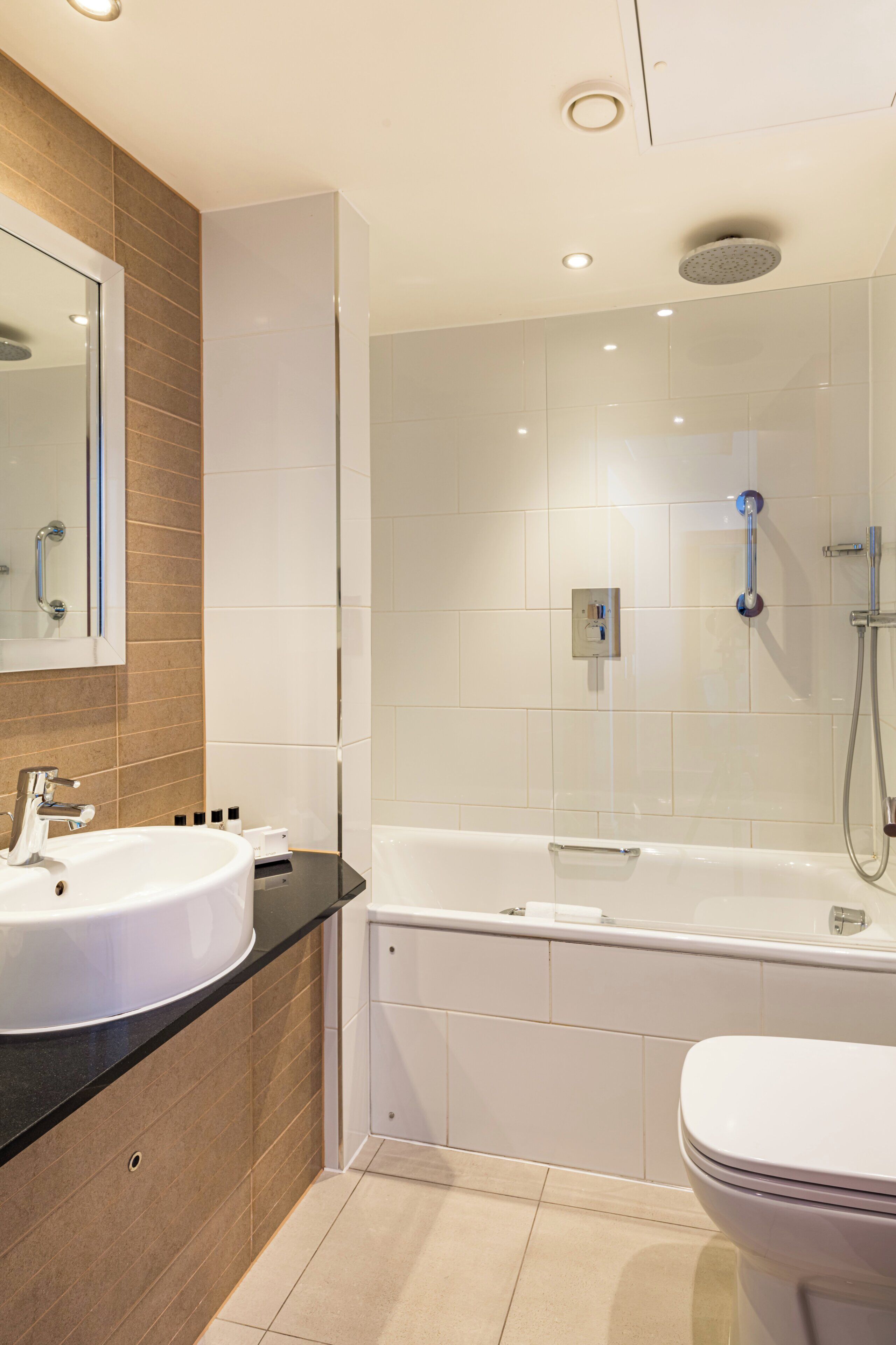 A modern bathroom with a sink, mirror, and bathtub.