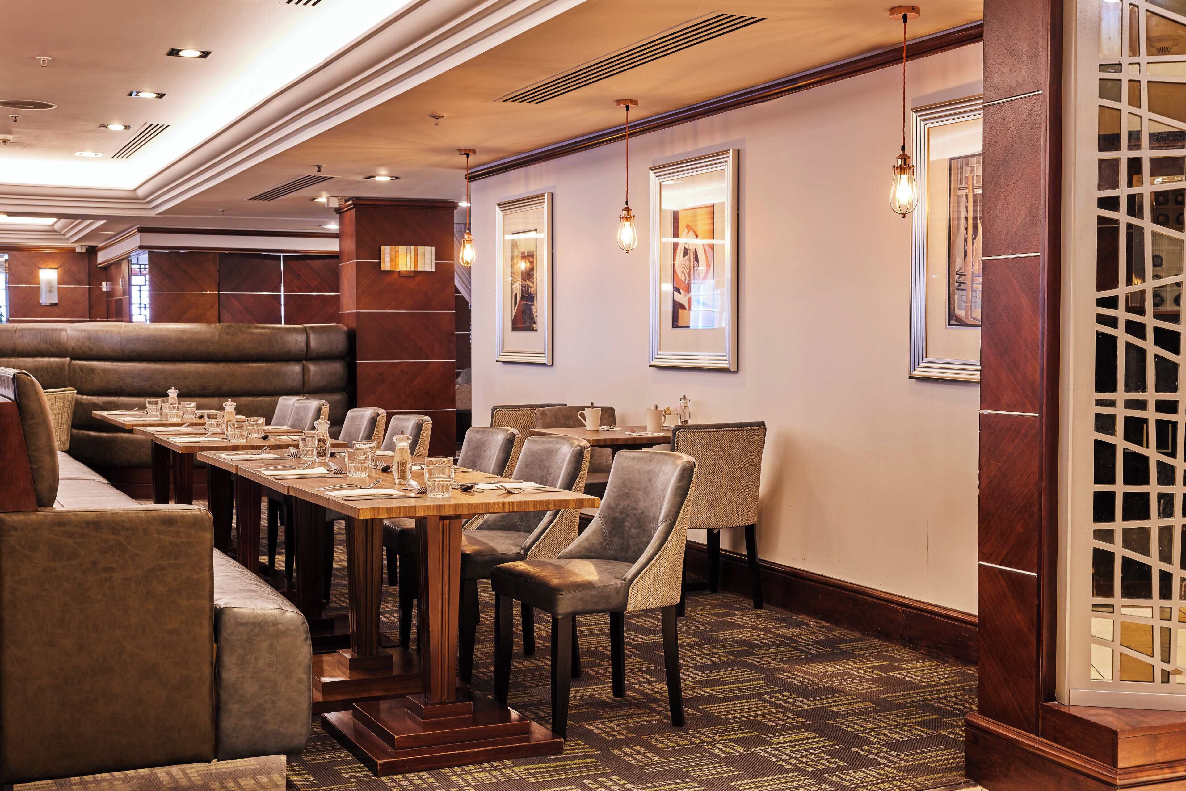 A restaurant with booths and tables, wooden flooring, and framed artwork on the walls.