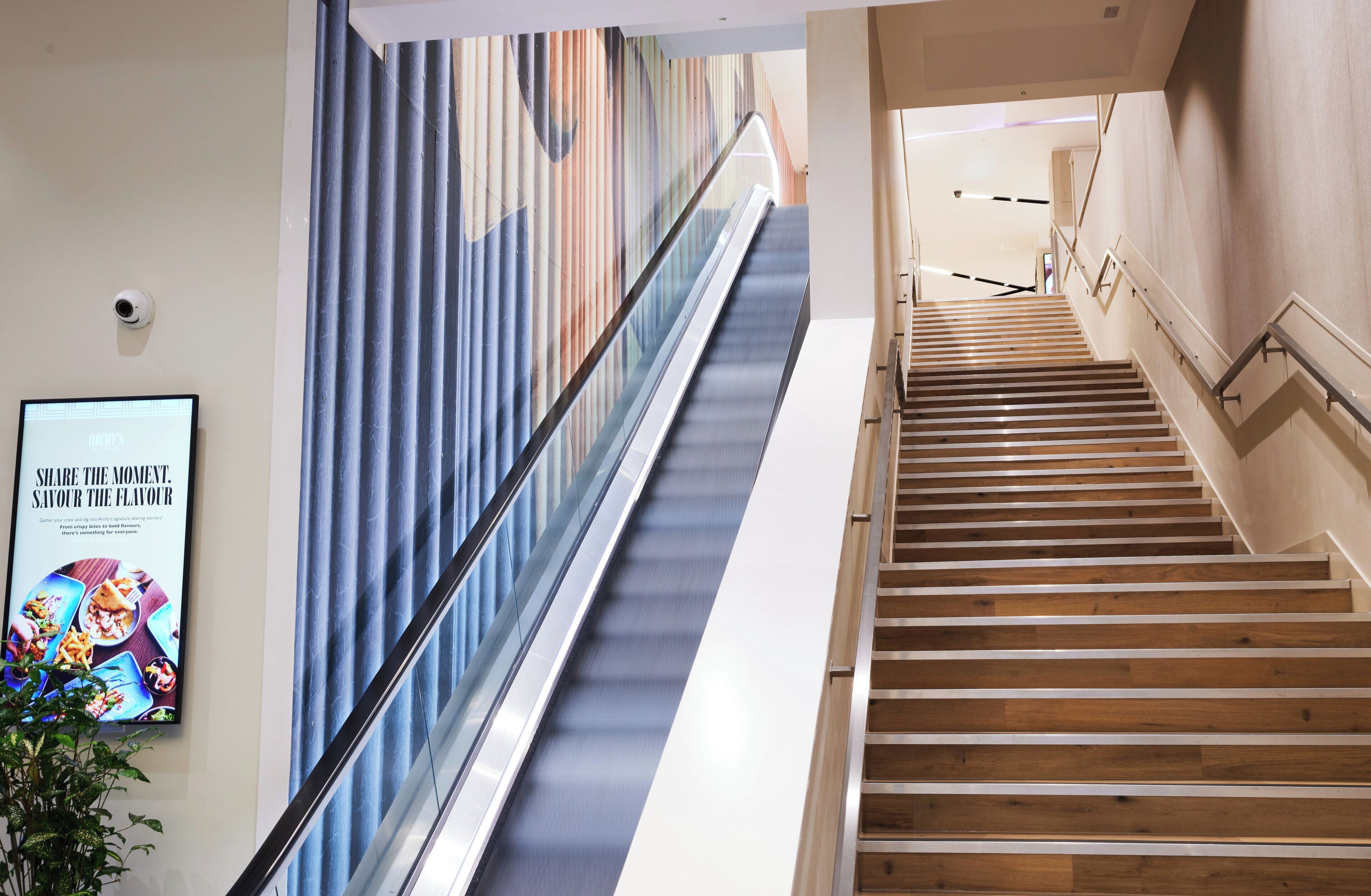 An indoor staircase with a wooden finish and a glass railing.