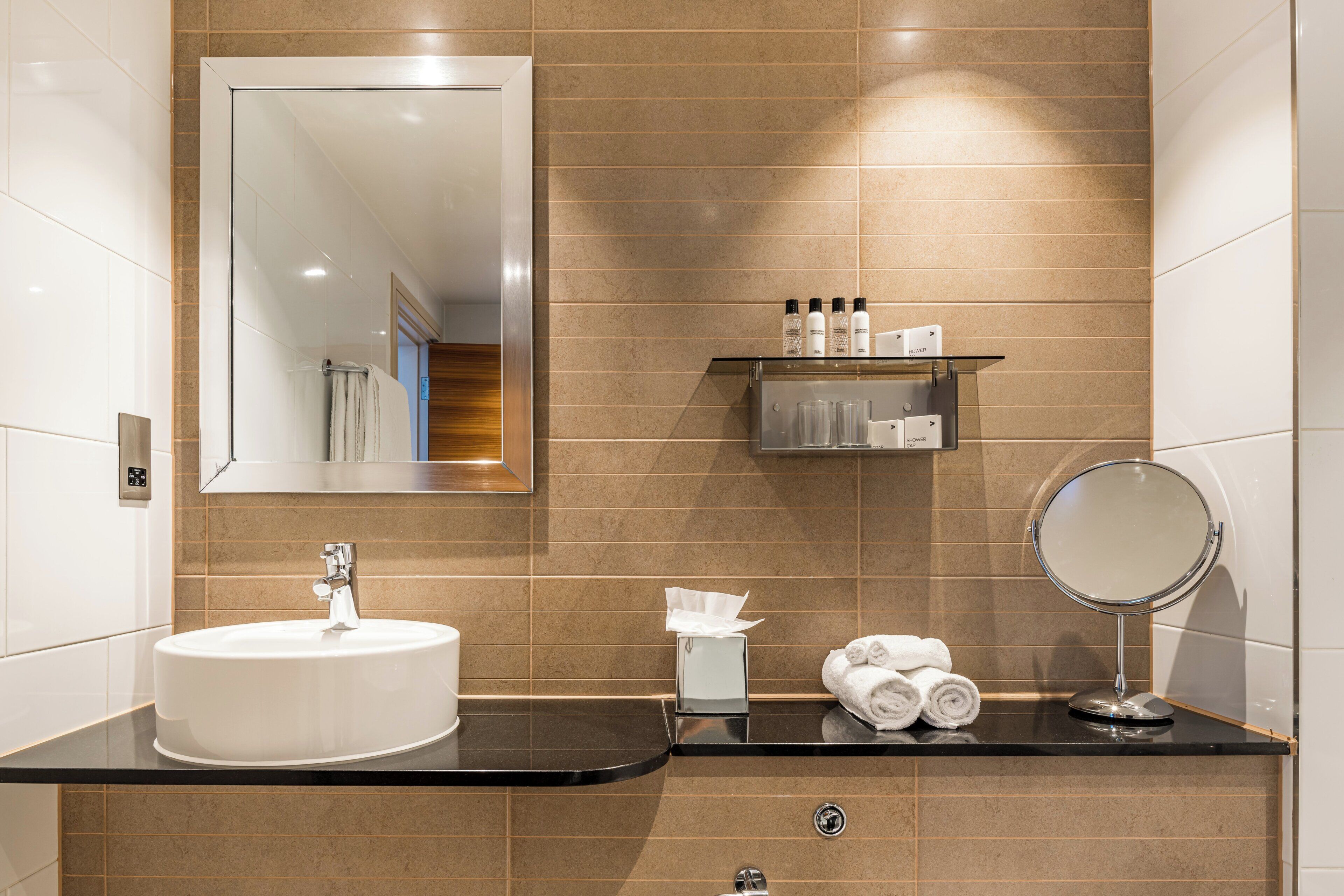 Une salle de bain moderne avec un lavabo blanc, un miroir et un porte-serviettes avec des serviettes.