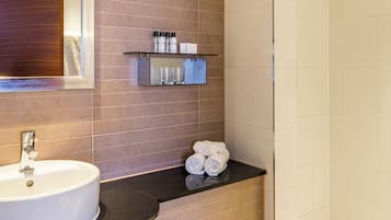 Un baño con lavamanos, espejo, toallero y zona de ducha.