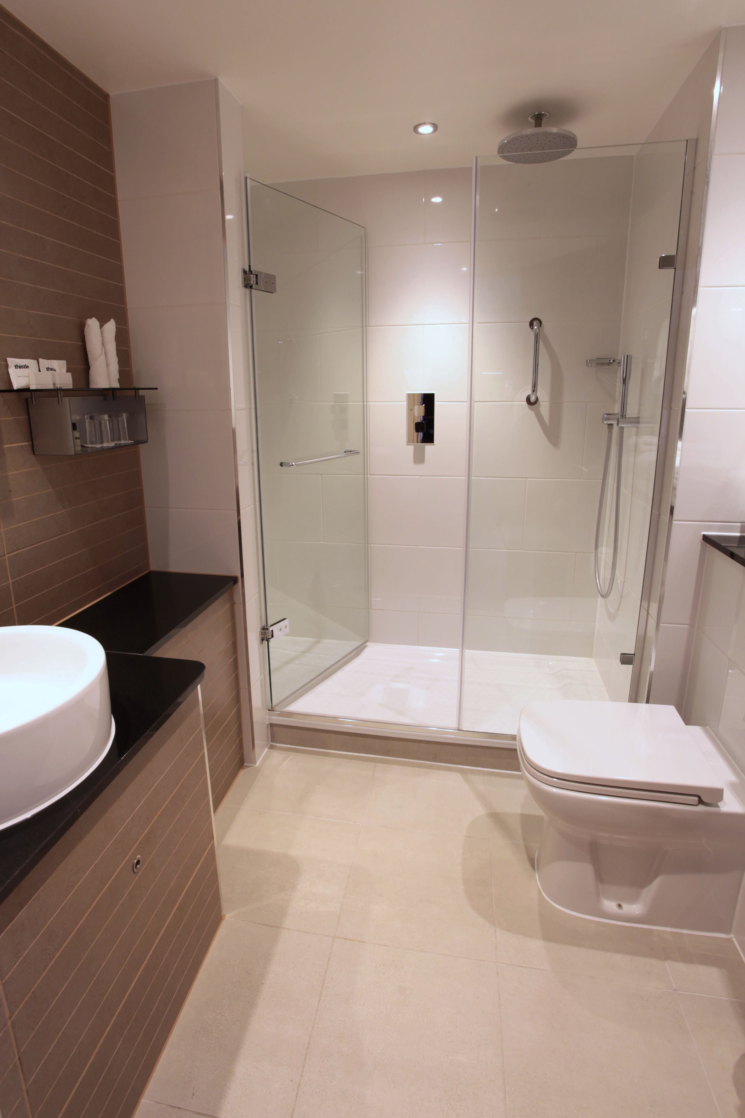 A modern bathroom with a glass-enclosed shower, a white toilet, and a black countertop with a sink.