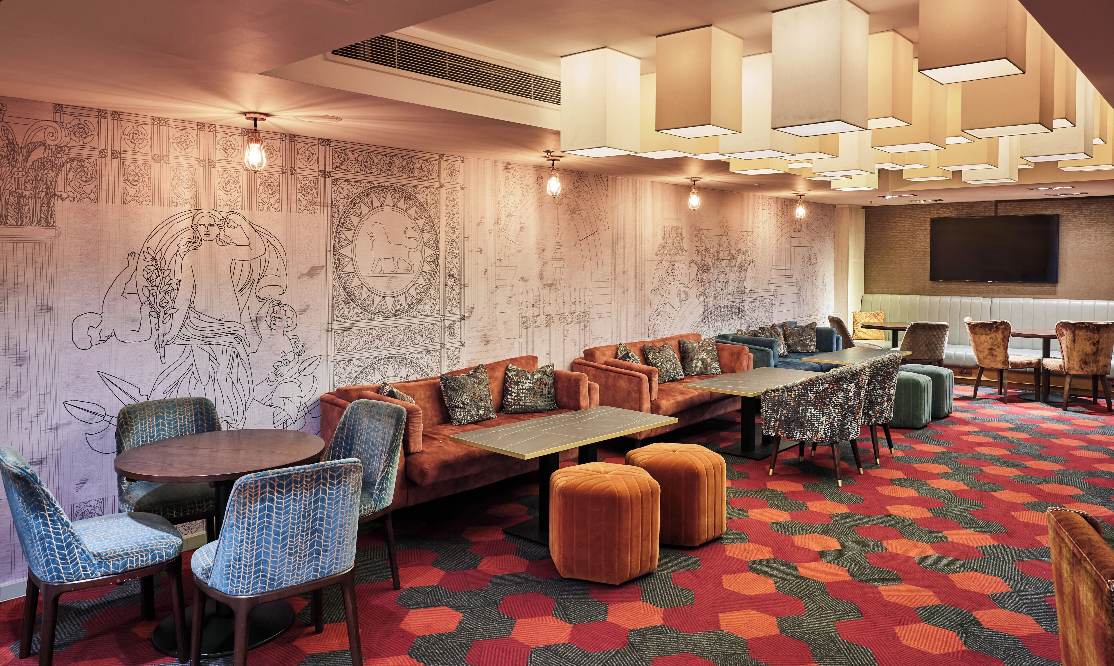 Un espacio lounge moderno con paredes decoradas, arreglos de asientos e iluminación ambiental.
