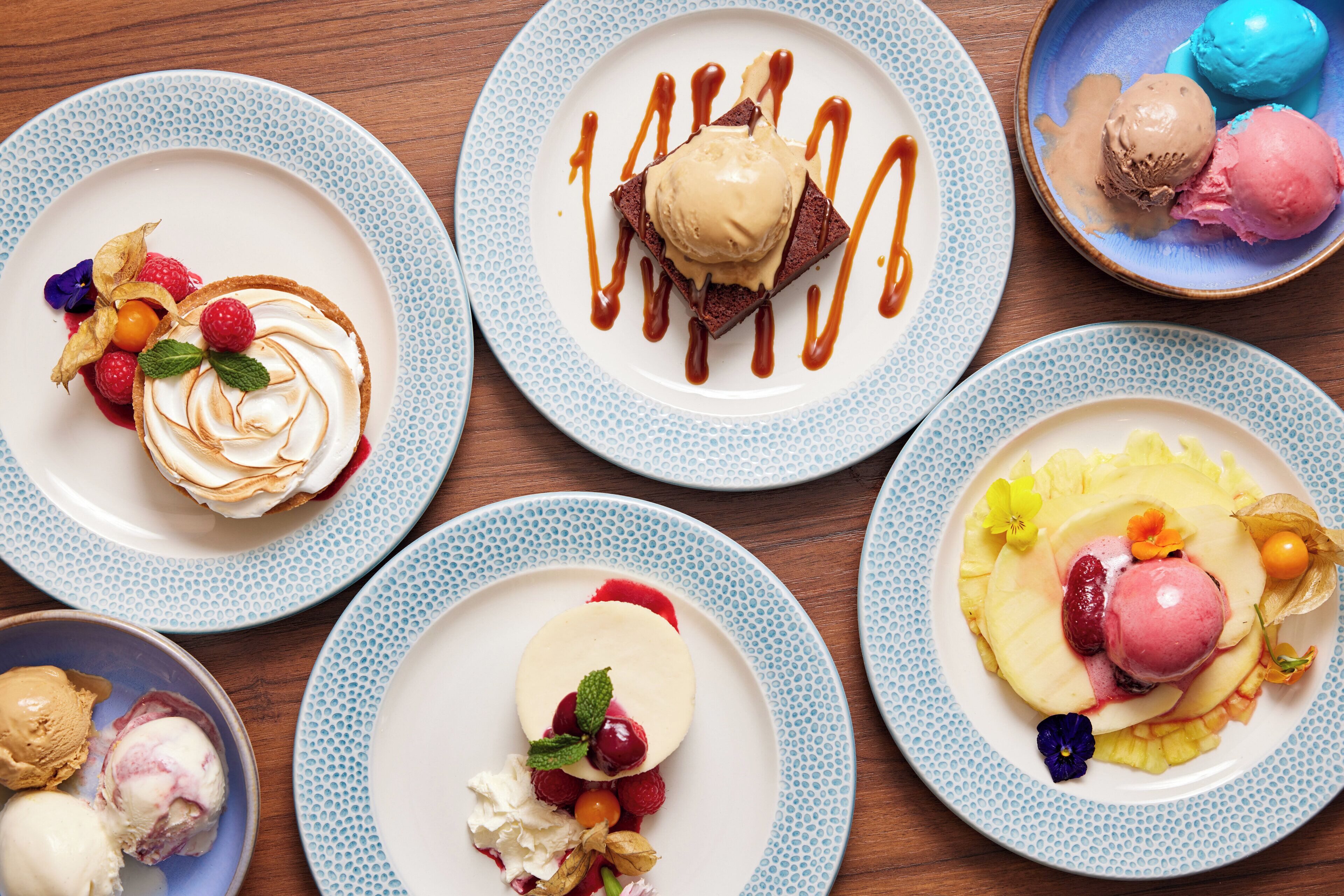 A variety of desserts on plates with different toppings and sauces.
