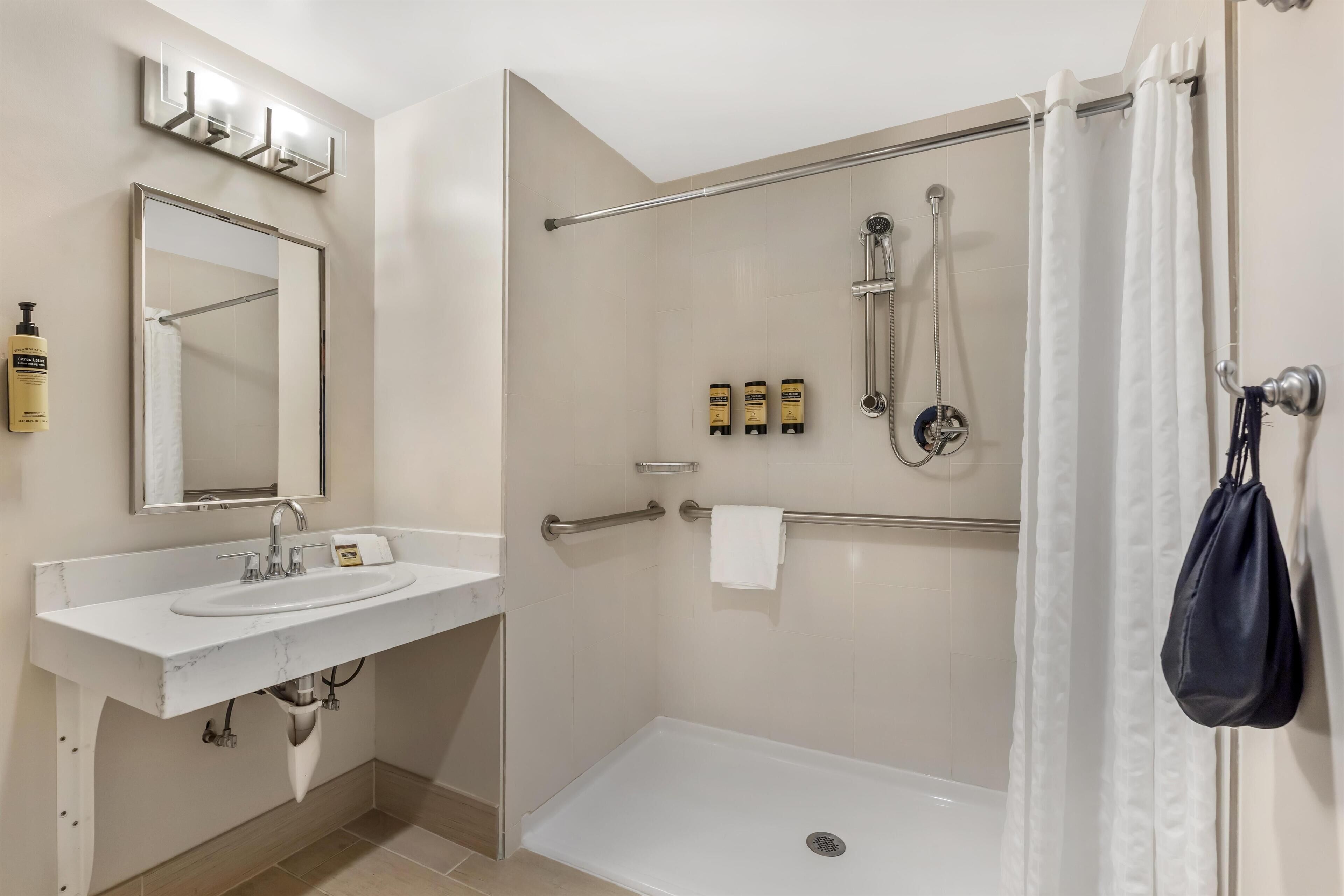 A modern bathroom with a white sink, mirror, and shower area.