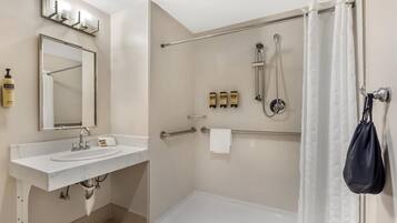 A modern bathroom with a white sink, mirror, and shower area.