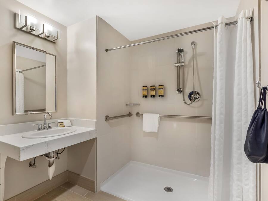 Une salle de bain moderne avec un lavabo blanc, un miroir et un espace douche.