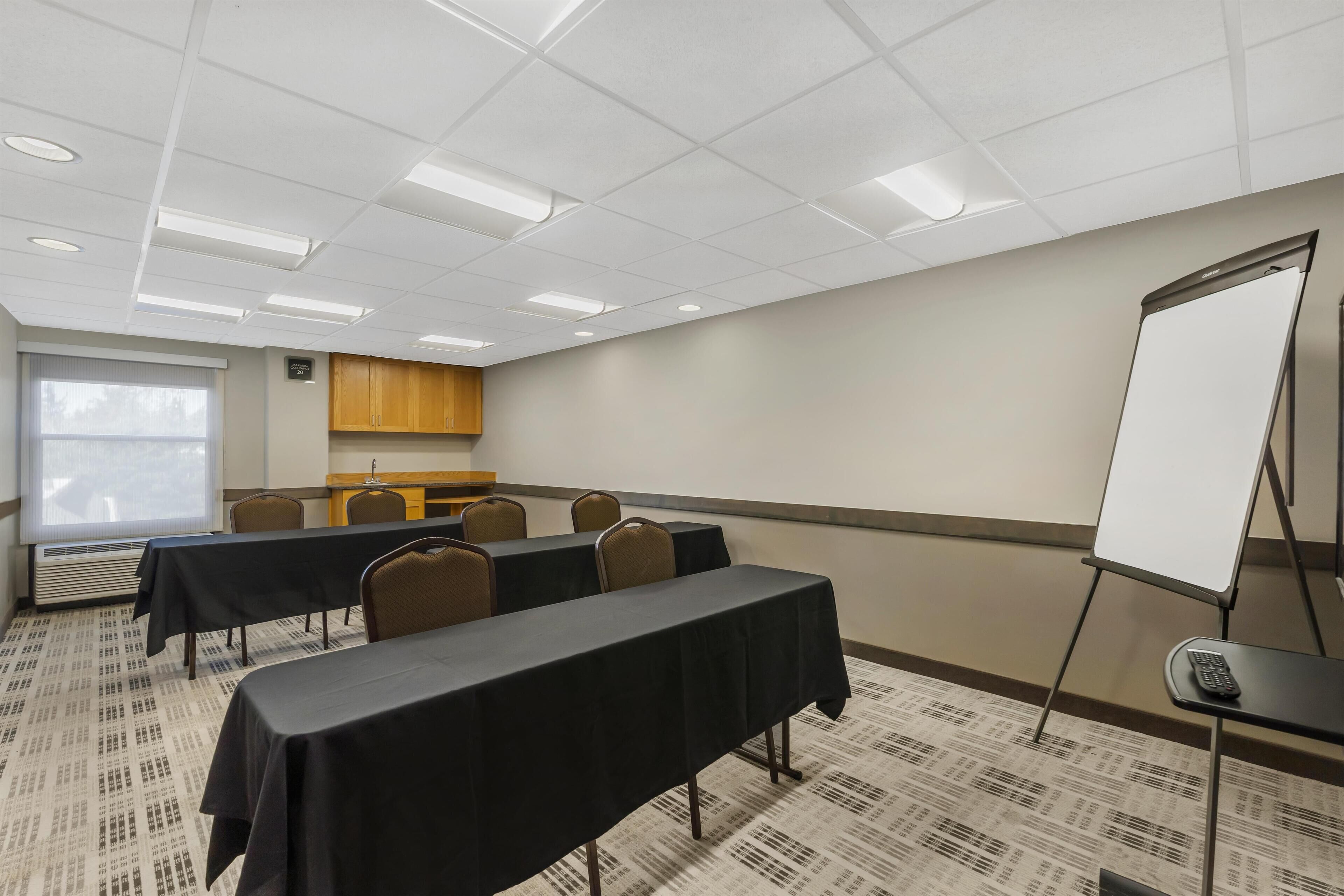 A conference room with a long table, chairs, a whiteboard, and a projector screen.