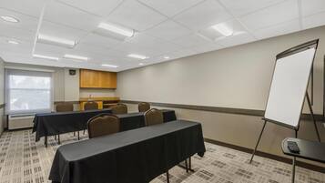 A conference room with a long table, chairs, a whiteboard, and a projector screen.