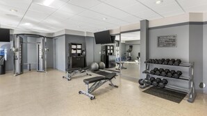 Ein Fitnessraum mit Trainingsgeräten, einer Bank und einem Hantelgestell.
