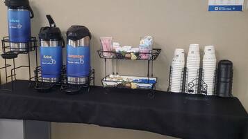 A breakfast bar with coffee dispensers, a clock, and a sign indicating face mask requirements.