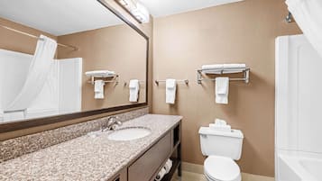 A bathroom with a granite countertop sink, a mirror, a toilet, and a shower area.
