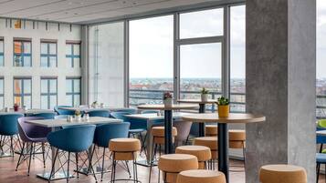 Ein modernes Interieur mit großen Fenstern, blauen Stühlen und runden Tischen.
