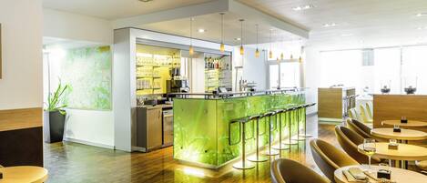 A modern restaurant with a bar area, wooden flooring, and bar stools.