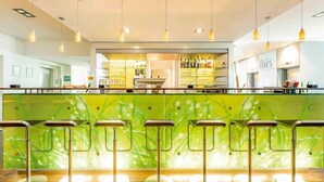 A modern bar area with green bar stools and a glass partition. - ibis Berlin Messe (Berlin)