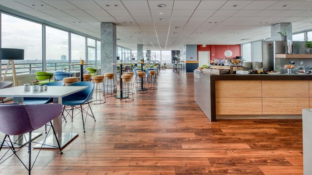 A spacious, modern cafeteria with high ceilings, large windows, and a variety of seating options. - ibis Berlin Messe (Berlin)