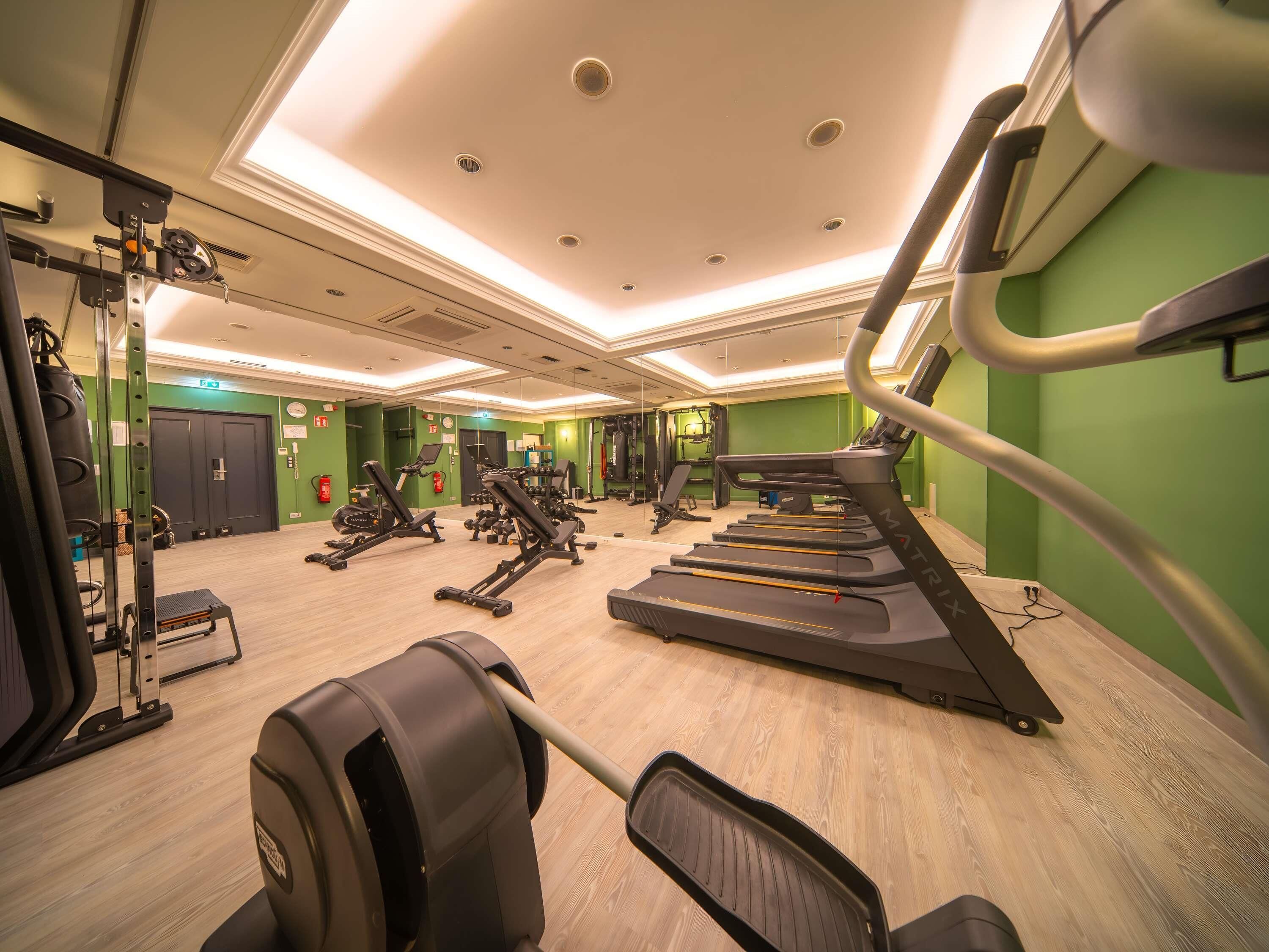 A gym with treadmills, weight machines, and a mirrored wall.
