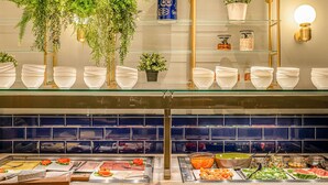 A buffet area with various food items, glass shelves with white bowls, and decorative plants. - Maek Hotel Antwerp Central - Handwritten Collection (Antwerp)