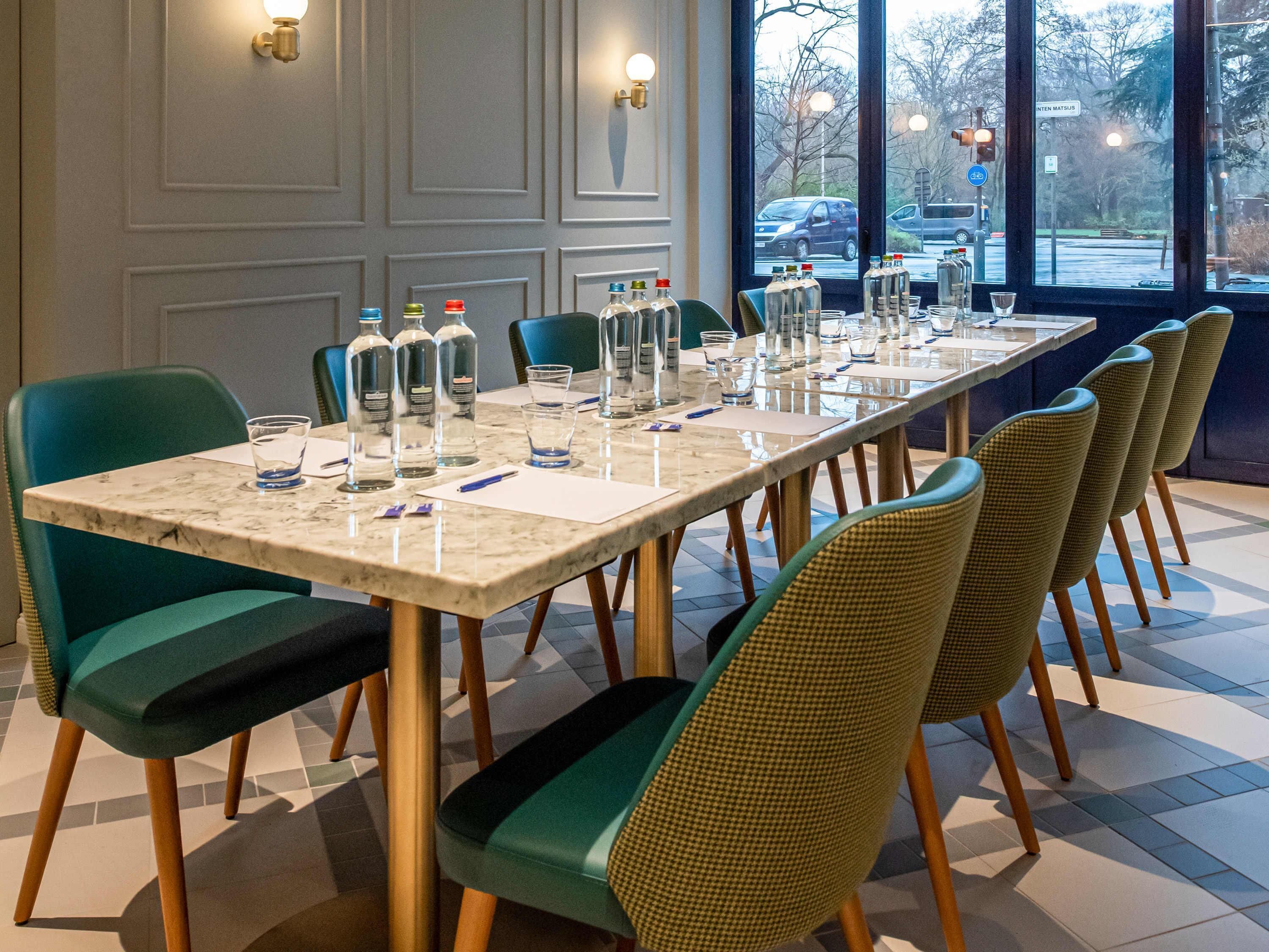 Une salle de conférence avec une longue table, des chaises et divers objets, comme des bouteilles et des verres.