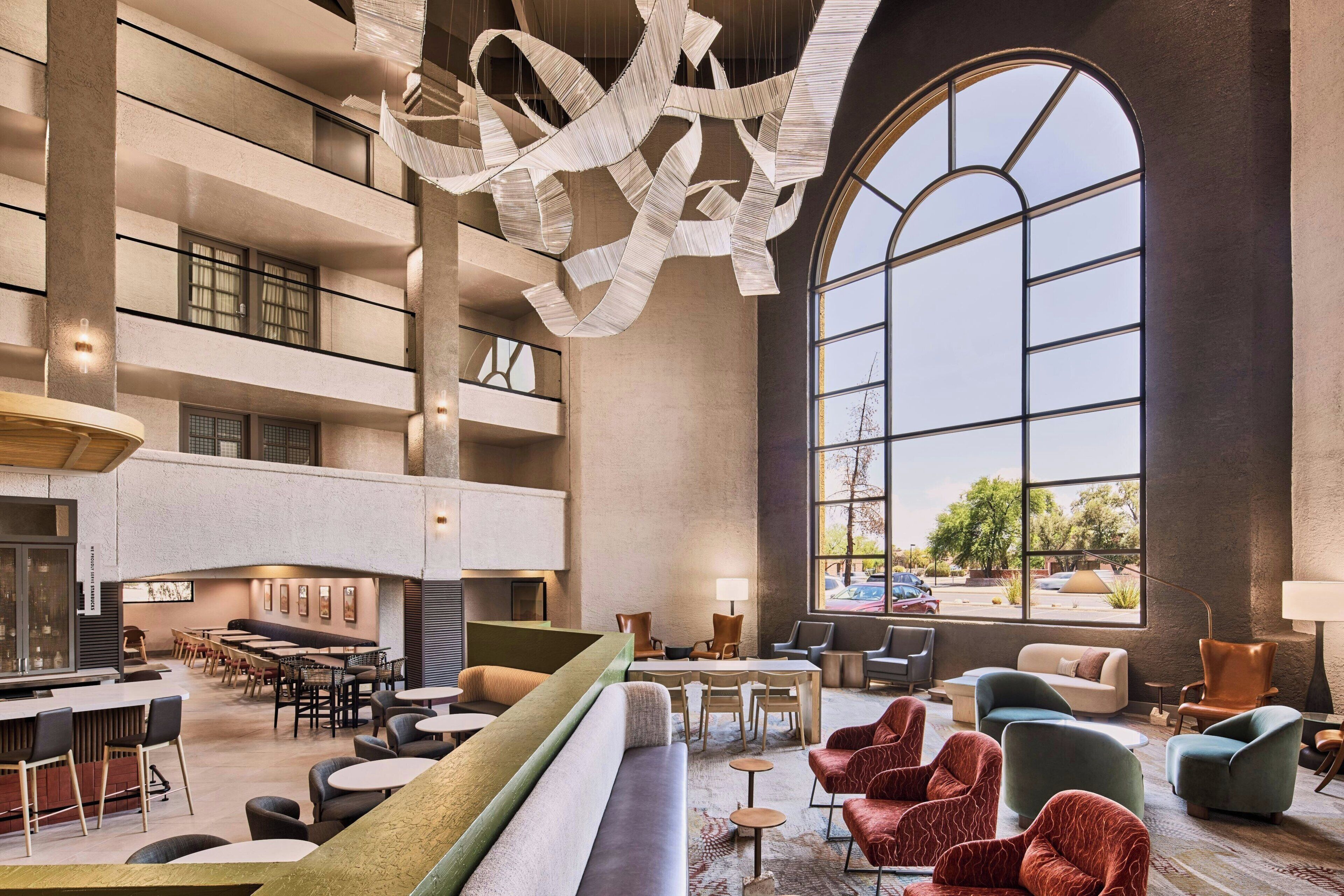 A spacious lobby with a high ceiling, large windows, and a modern chandelier.