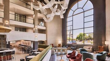 A spacious lobby with a high ceiling, large windows, and a modern chandelier.
