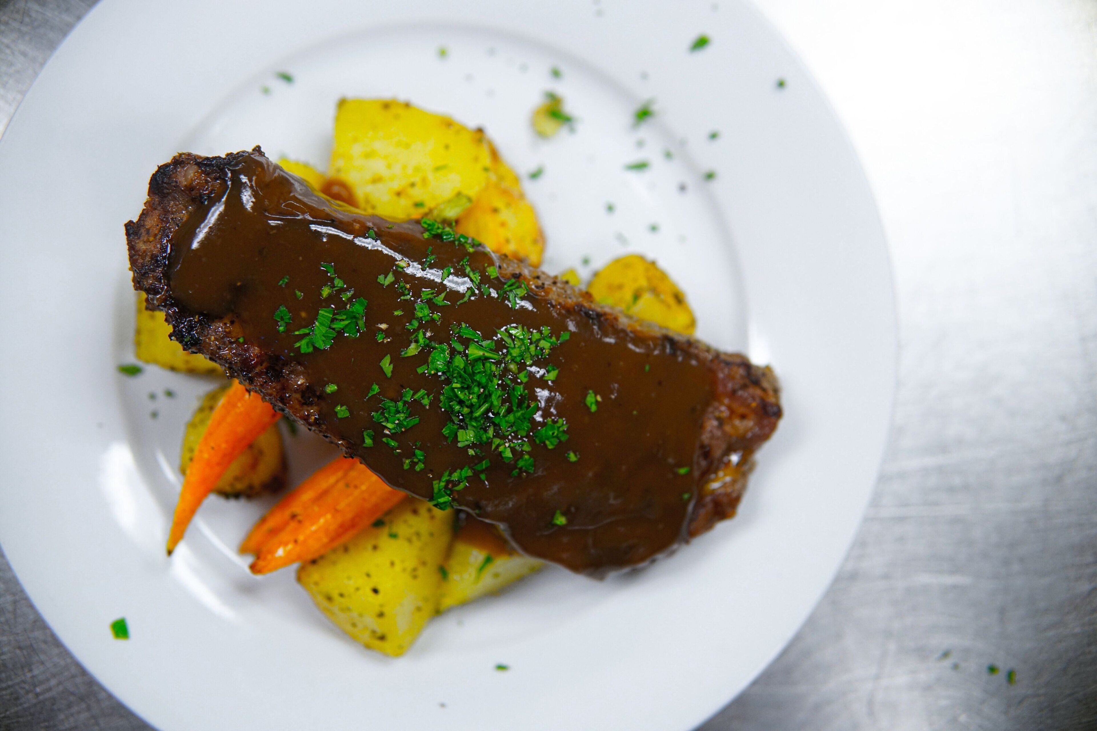 Une assiette contenant un plat de viande, des pommes de terre et des carottes.