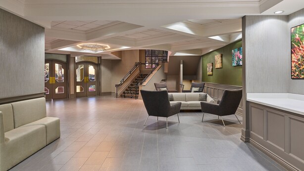 A spacious lobby with a high ceiling, a staircase, and a seating area with sofas and chairs. - Sheraton Tucson Hotel and Suites (Tucson)