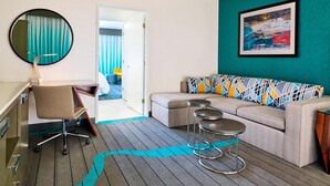 A modern hotel room with a desk, office chair, sofa, and two bar stools. - Sheraton Tucson Hotel and Suites (Tucson)