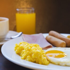 Savor a hearty breakfast with scrambled eggs, sunny-side-up eggs, and sausages.