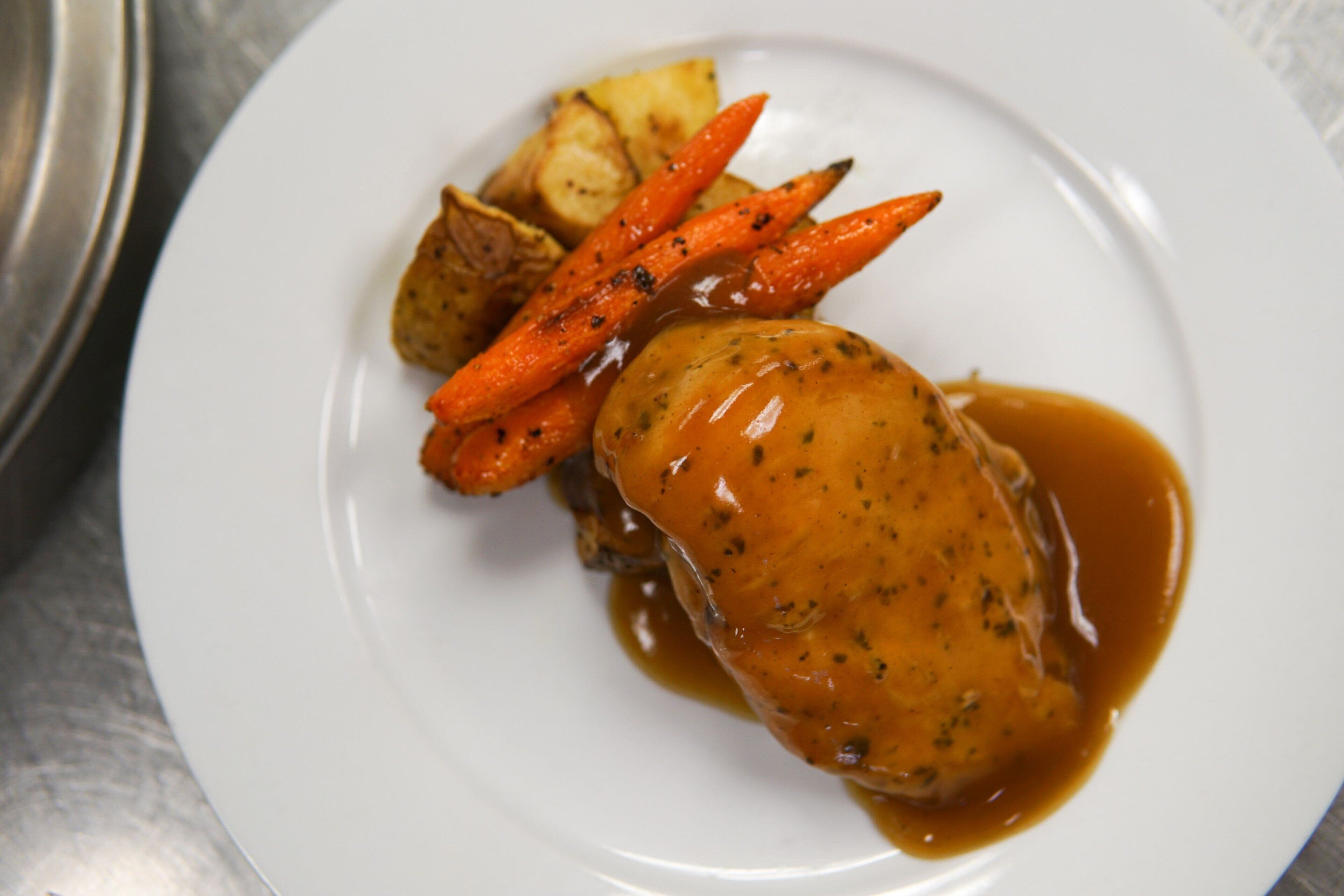 A plate with a piece of meat, carrots, and potatoes.