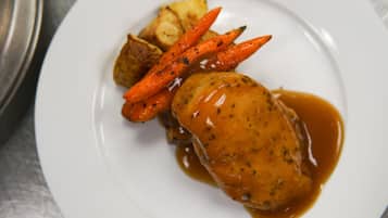 A plate with a piece of meat, carrots, and potatoes.