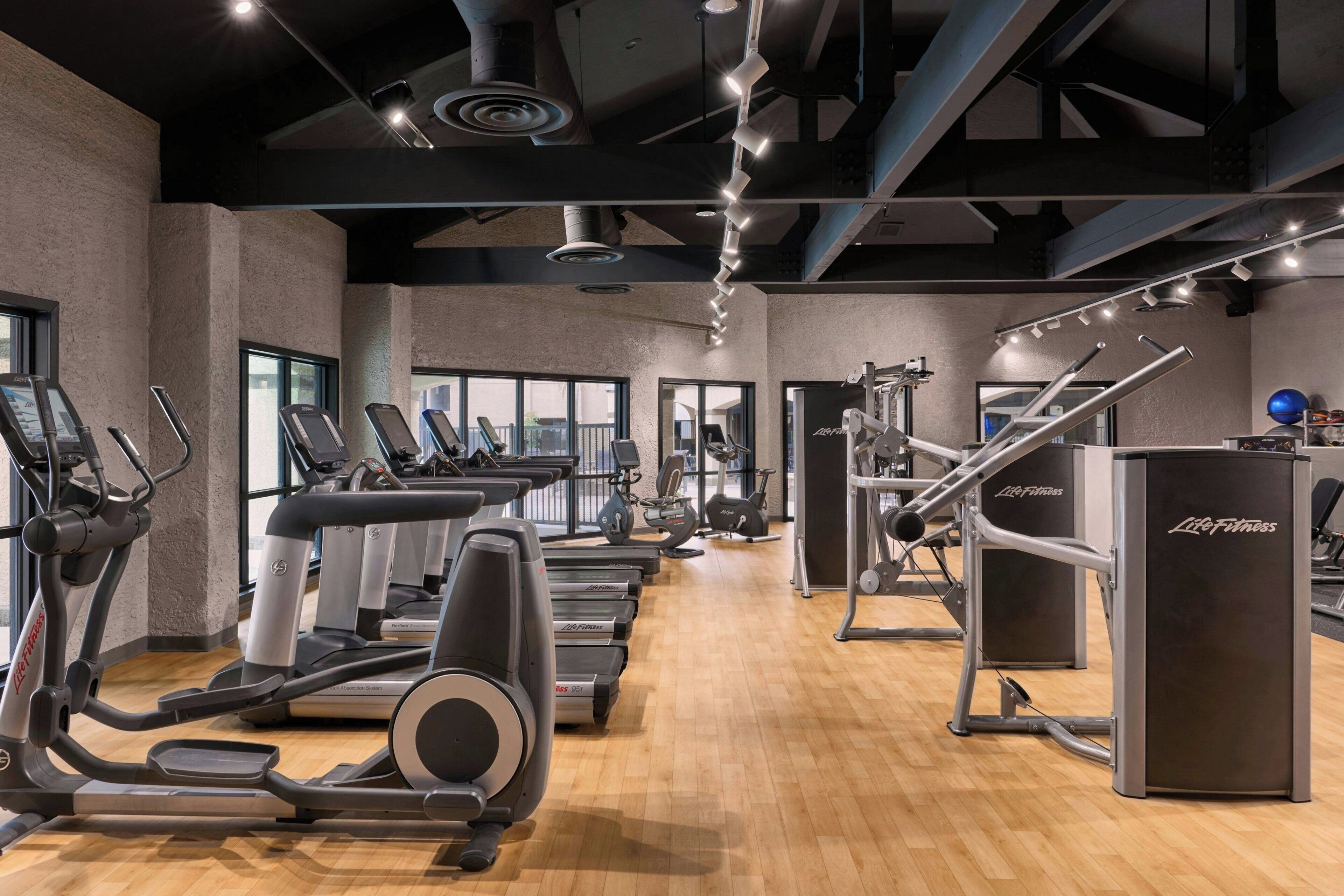 Un gimnasio con cintas de correr, elípticas y máquinas de pesas.