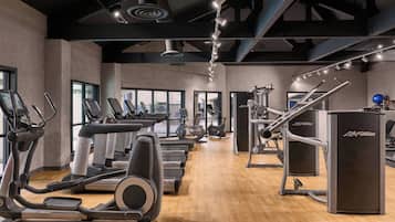 Un gimnasio con cintas de correr, elípticas y máquinas de pesas.