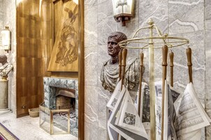 A marble lobby with a statue, a fireplace, and a chandelier.