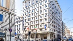 Un hotel de varios pisos con un estilo arquitectónico clásico, que presenta una entrada destacada y varios balcones.