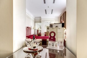 A hotel lobby with a reception desk, a red upholstered sofa, and a tray with wine glasses and bottles.