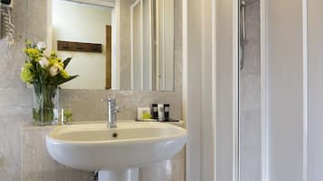 Un bagno con lavandino bianco, uno specchio e una doccia.