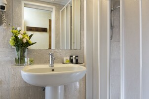 A bathroom with a white sink, a mirror, and a shower.