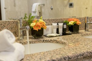 A bathroom with a granite countertop, a sink, a mirror, and a towel rack.