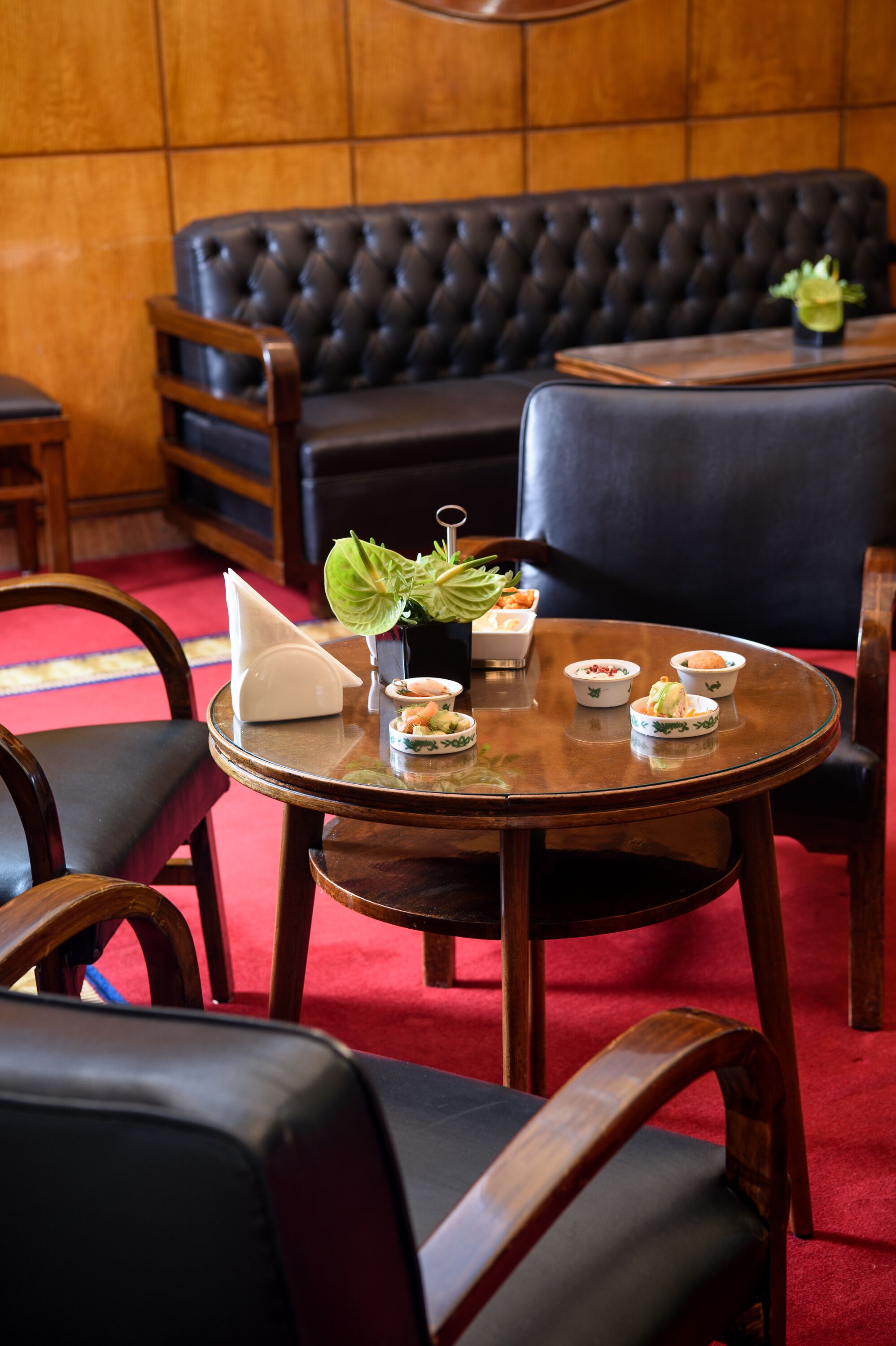 A dining area with a round table set for a meal, surrounded by leather chairs.