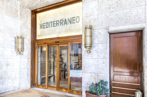 A hotel entrance with a sign reading "Albergo Mediterraneo" and a wooden door.