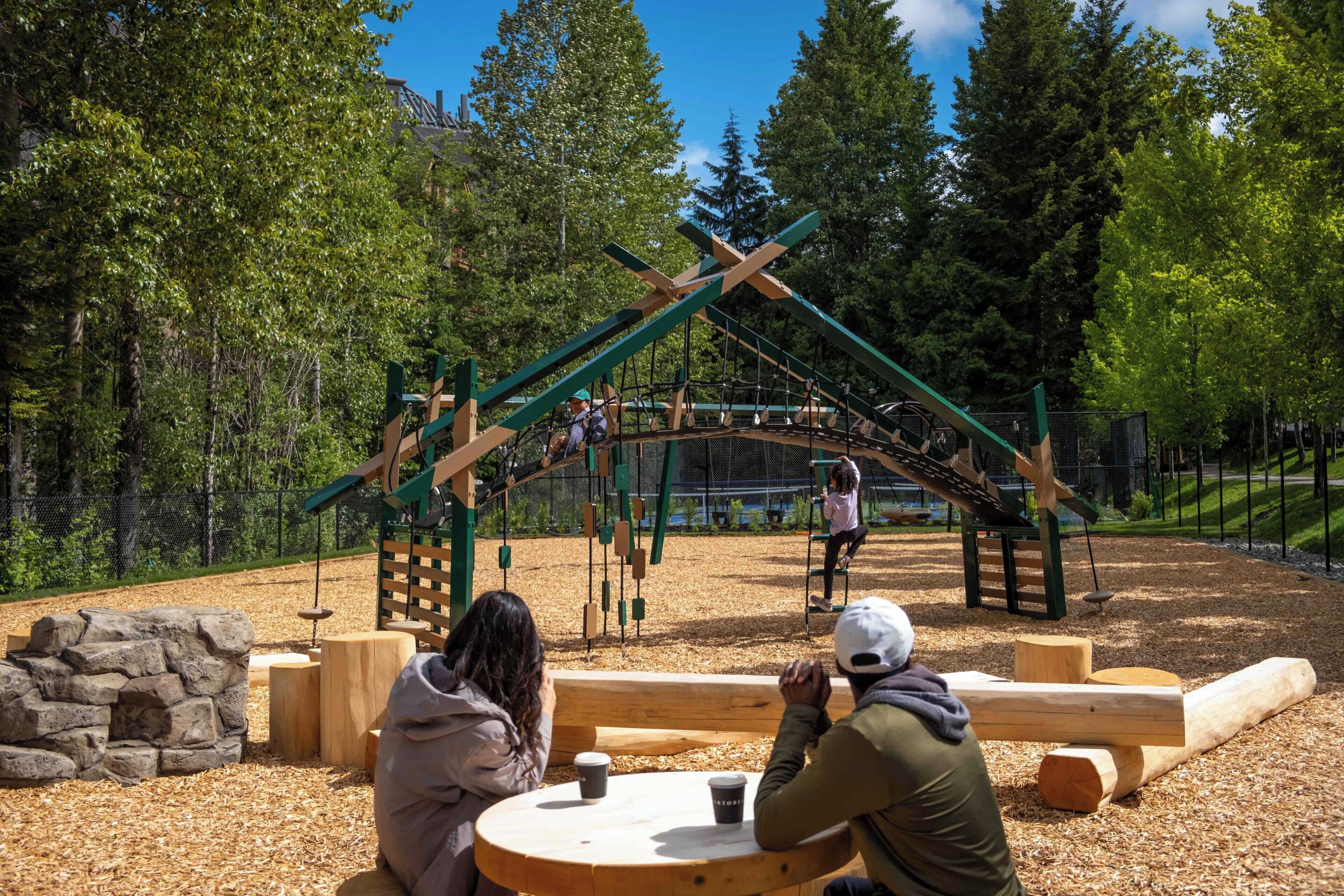 A playground with wooden structures and a stone wall.