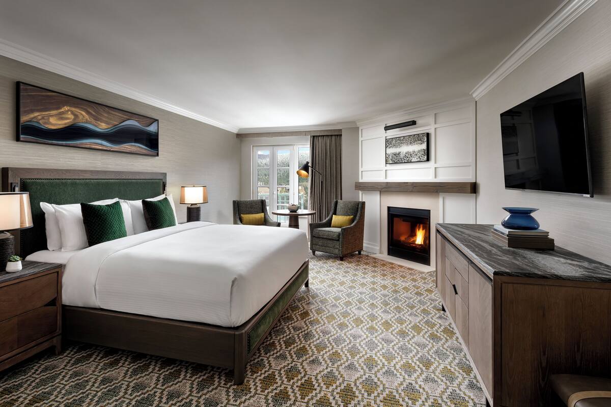 Une chambre d’hôtel avec un grand lit, une cheminée, une télévision et une vue sur l’extérieur.