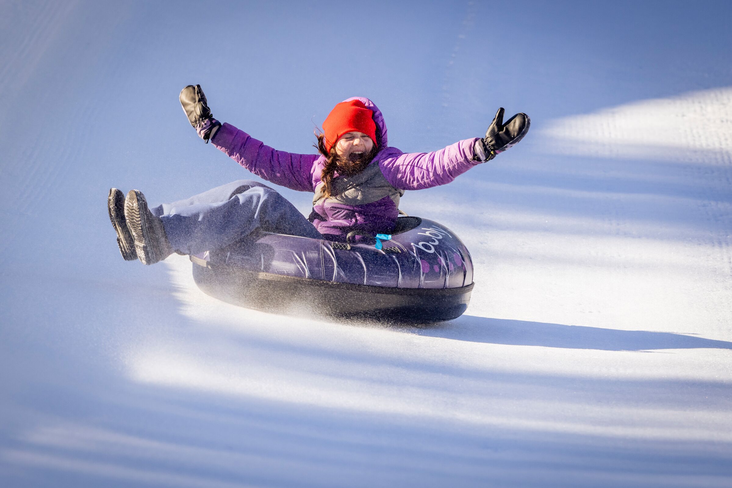 A person snow tubing on a snowy slope.