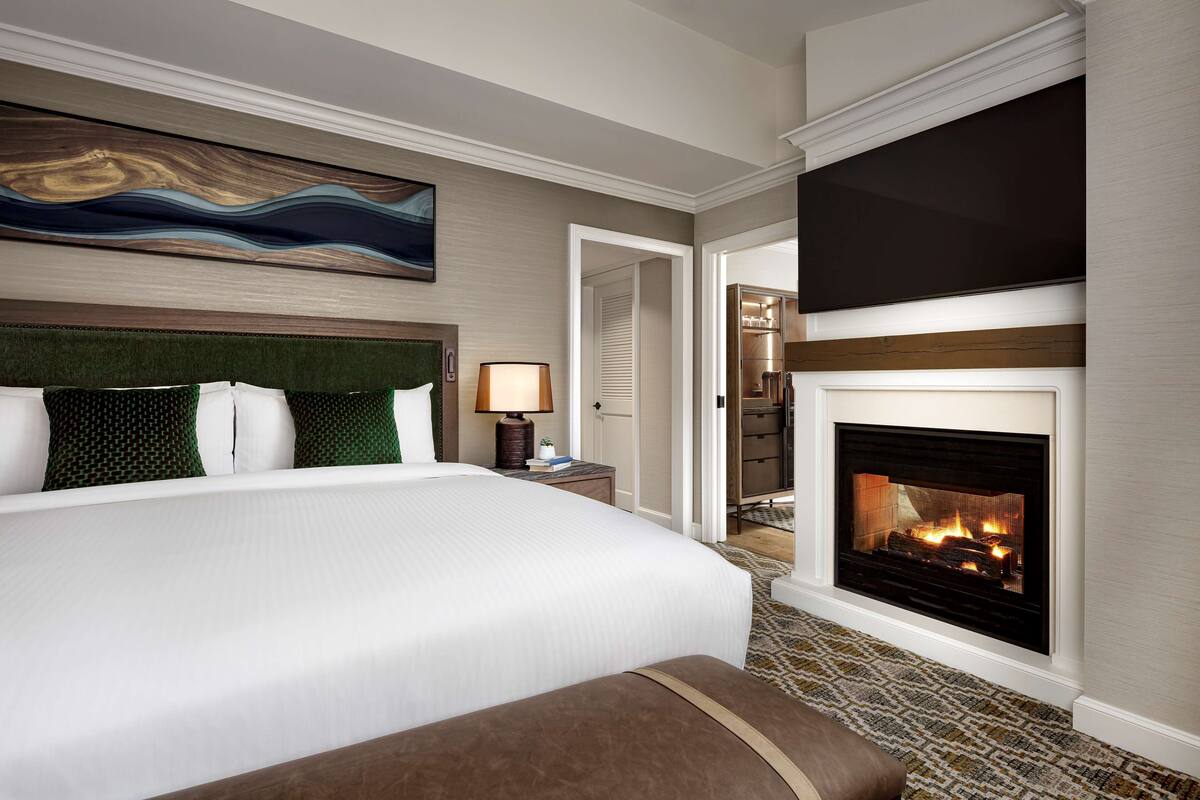 Une chambre d’hôtel dotée d’un grand lit, d’une cheminée et d’un décor moderne.